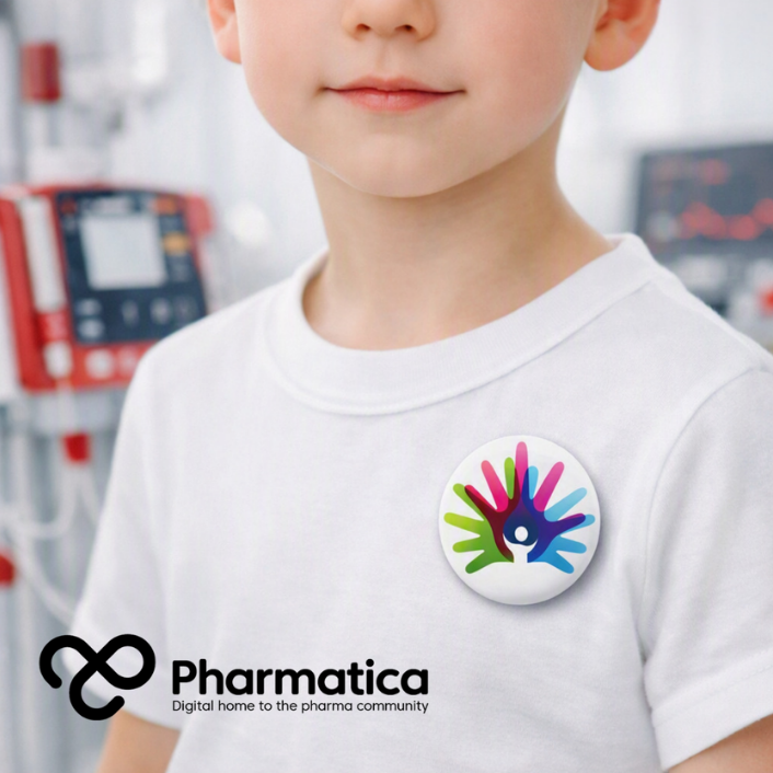 Pharmatica close-up image of a young child wearing a white T-shirt with a Rare Disease Day badge, seated in a bright clinical home environment with red medical devices in the background, representing rare disease care, patient independence, and humanitarian medical technology.